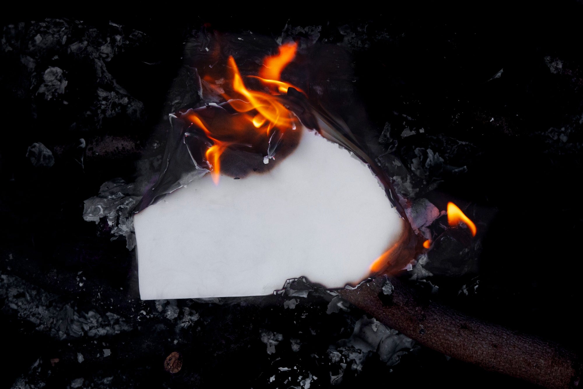 paląca się kartka papieru na ciemnym tle